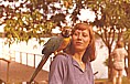 1975_PERU_zugeflogener Papagei l&auml;sst sich auf Angelikas Schulter nieder_gerade hat er ihre Hals-Holzkette geknackt und die H�lfte der exakt halbierten Kugel geklaut_Lago Yarinacocha bei Pucallpa, nahe Rio Ucayali, Zufluss zum AMAZONAS_Reise per Rucksack durch KOLUMBIEN, ECUADOR, PERU, BOLIVIEN und CHILE